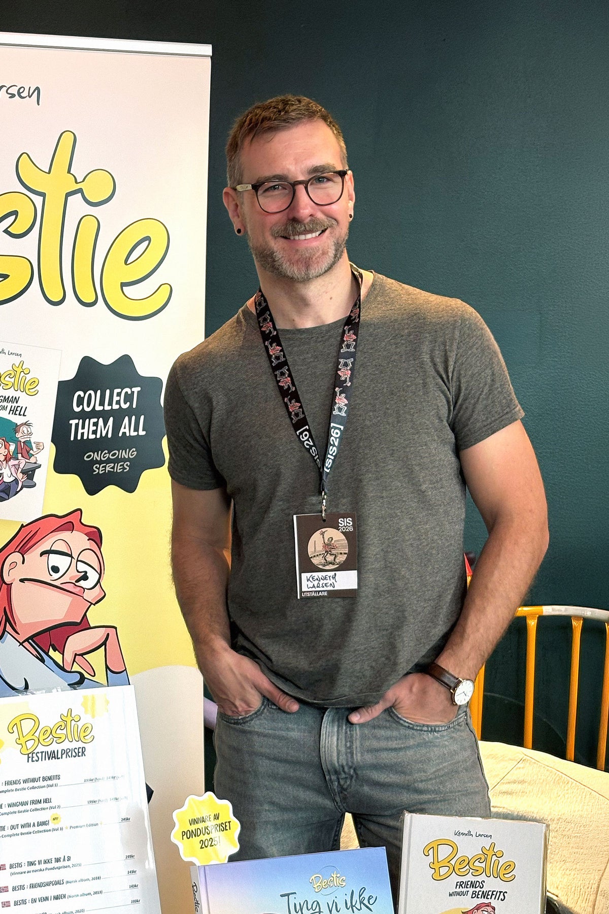Comic creator Kenneth Larsen smiling at the Silverstone Comics booth during the Stockholm International Comics Festival 2026, featuring printed volumes of Bestie on display.